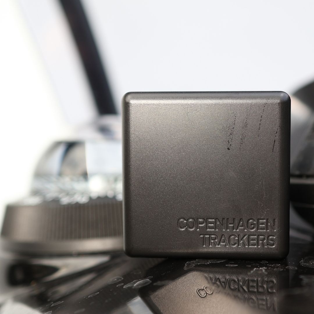 Cobblestone GPS tracker with 'Copenhagen Trackers' branding on a reflective surface