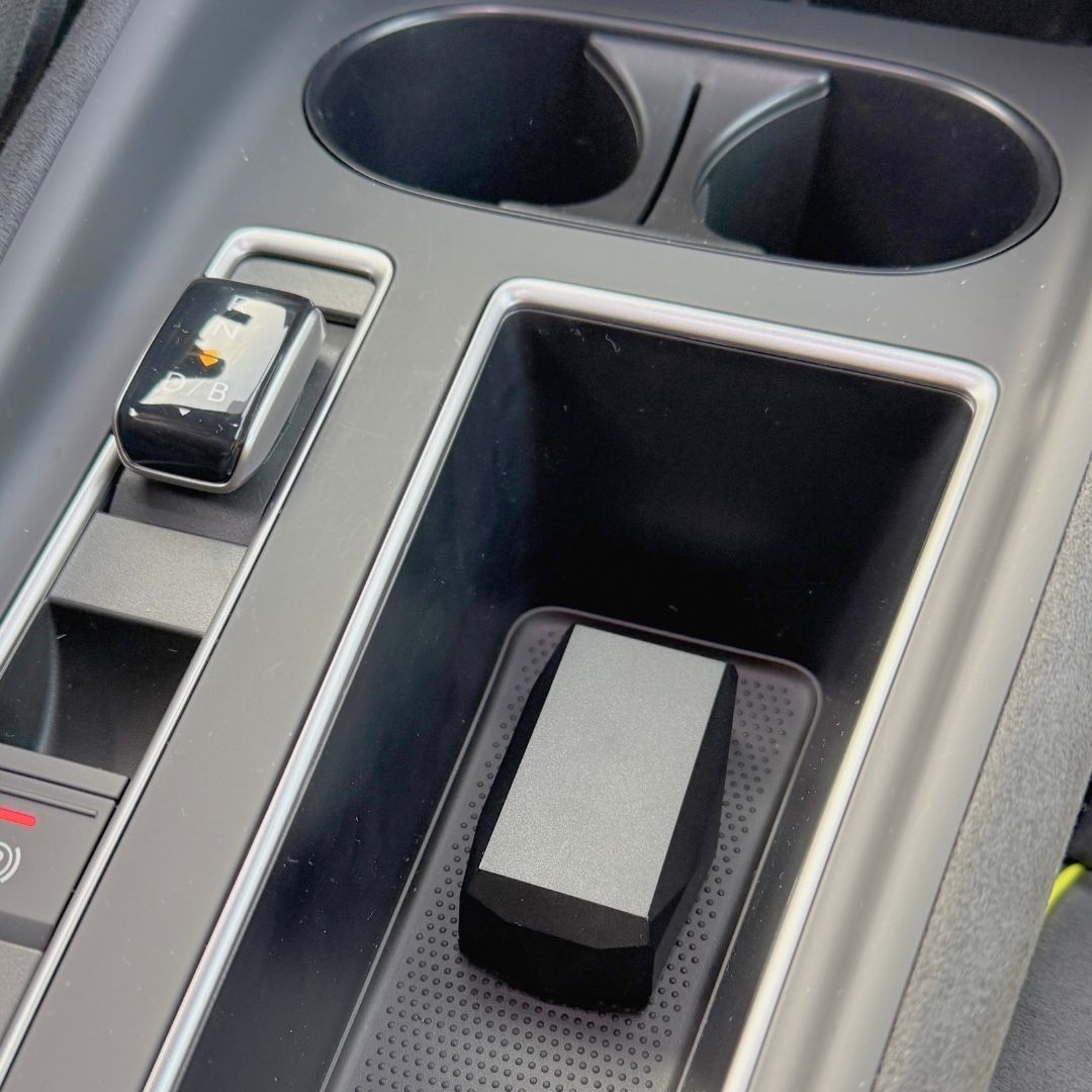 Close-up of a car's center console with a GPS-tracker lying in it.