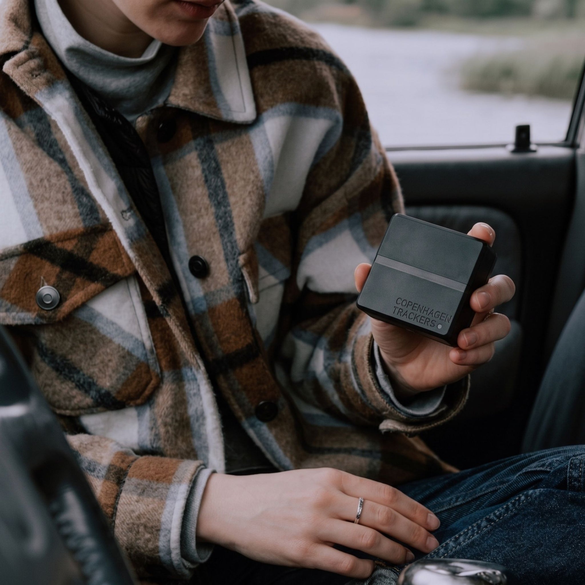 Persona con in mano il localizzatore GPS Cobblestone 2.0, seduta all’interno di un veicolo.
