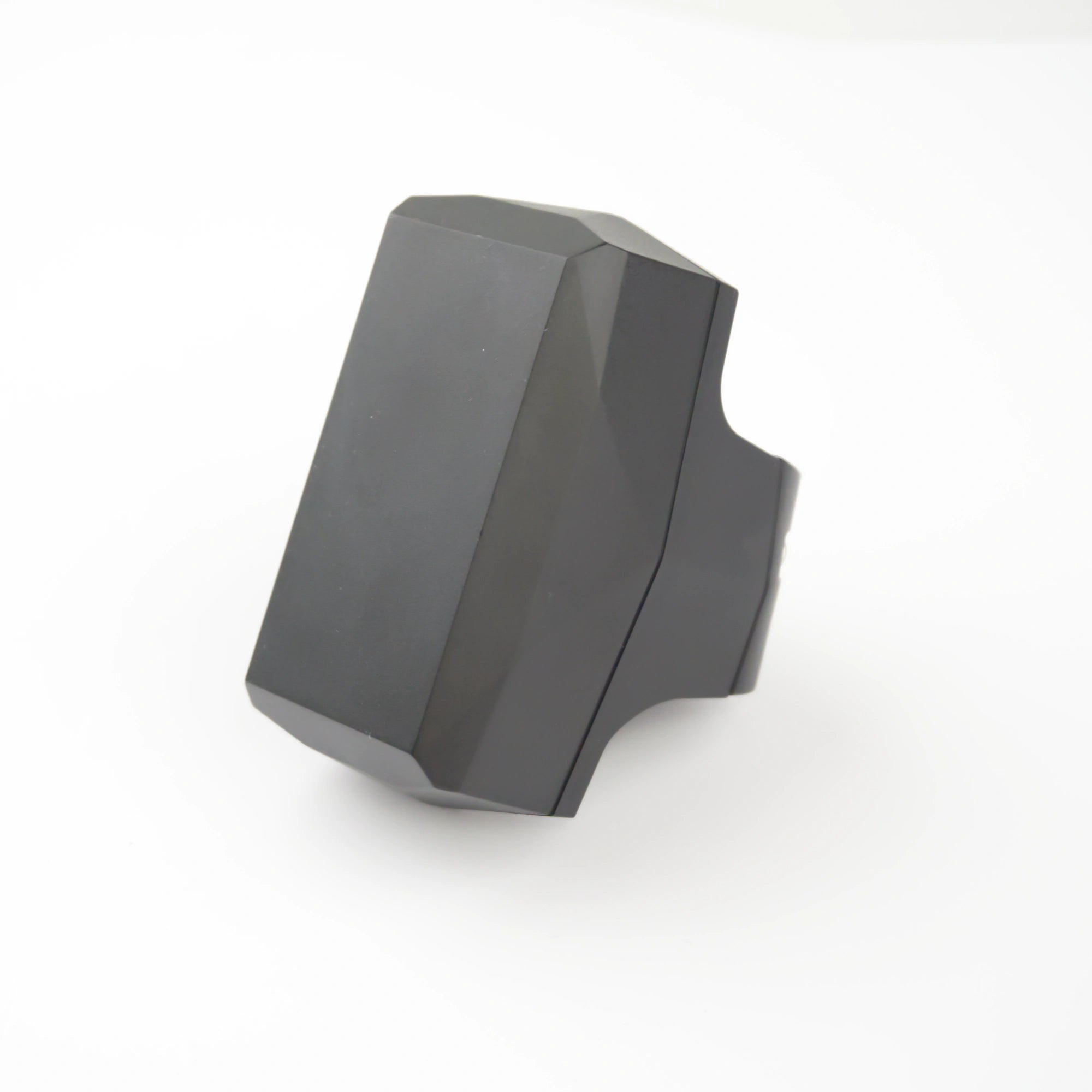 Gemstone GPS-tracker; een donkergrijs, gefacetteerd, geometrisch, ringvormig voorwerp, afgebeeld tegen een effen witte achtergrond.