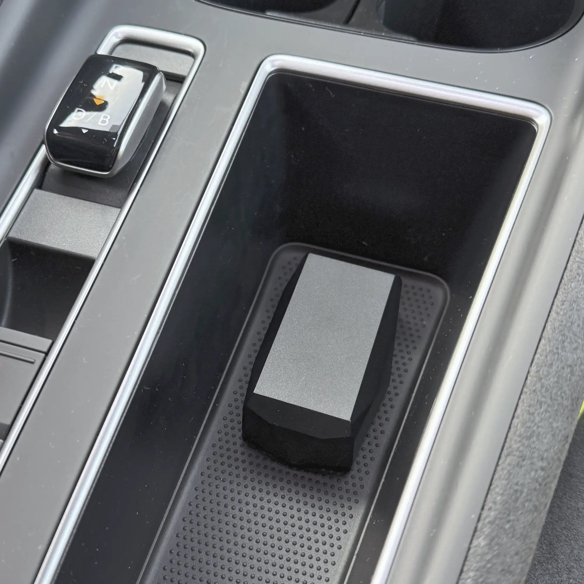 Localizador Gemstone dentro de una bandeja organizadora para la consola central del coche con ribete plateado.
