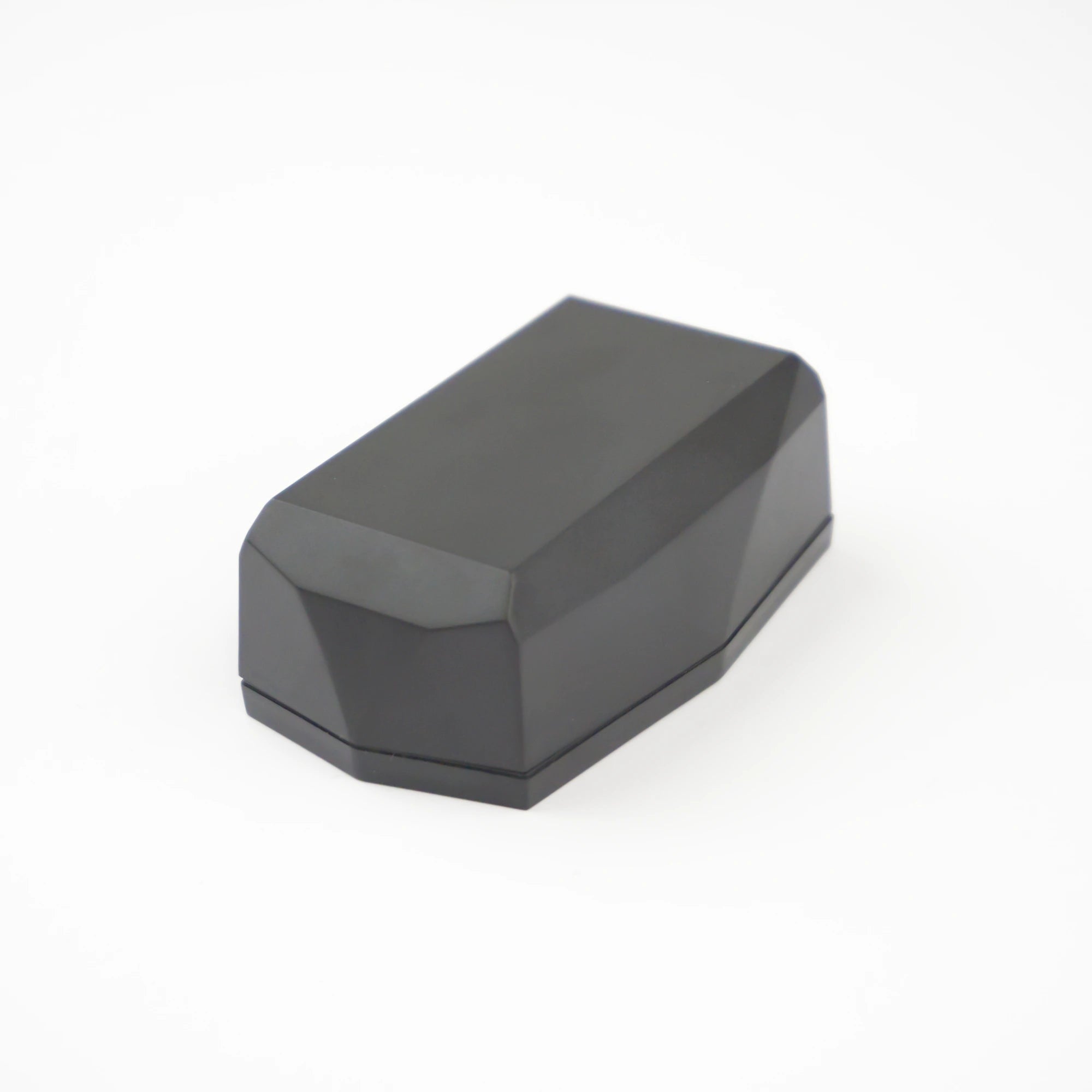 Localizador Gemstone »: una caja rectangular facetada de color gris oscuro con un diseño geométrico similar al de un diamante, sobre un fondo blanco sin bordes.